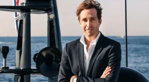Martin Hager, mit verschränkten Armen auf einem Boot, blickt zuversichtlich in die Kamera.