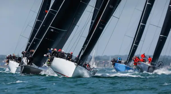 Segelboote kämpfen um die Admirals Cup. Schwarze Segel dominieren, während Teams auf dem Wasser um den Sieg ringen.