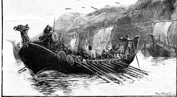 Eine Flotte von Wikingerschiffen mit Drachenköpfen auf den Bugspitzen, besetzt mit Kriegern und Ruderern, segelt auf dem Meer.