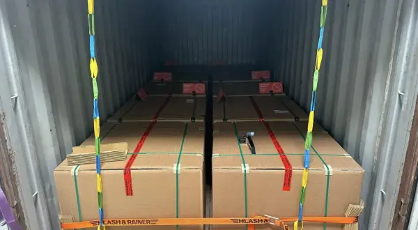Ladungssicherung in einem Frachtcontainer: Mehrere große Kartons, gesichert mit Gurten und Ketten. Verschiedene Arten von Containern werden hier für den Transport genutzt.