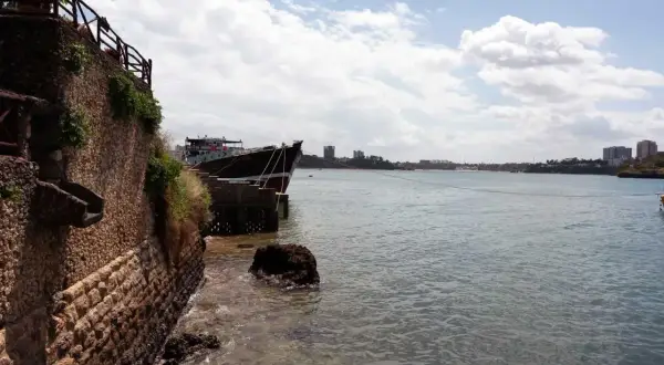 Ein Schiff liegt im Hafen von Mombasa vor Anker. Die Steinküste und Gebäude im Hintergrund zeugen von der geschäftigen Atmosphäre.