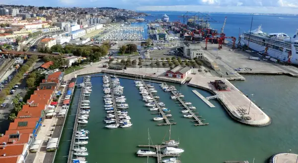 Blick auf den geschäftigen Lissabon Port mit vielen Segelbooten und einem Kreuzfahrtschiff.