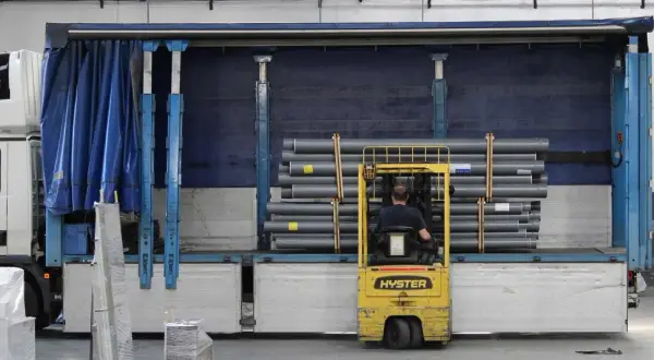 Gabelstapler lädt Rohre in einen LKW. Die Ware wird für den Versand vorbereitet, um die notify party zu informieren.