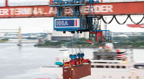 Ein großer Kran hebt einen Container im Mumbai Port. Die HHLA-Beschriftung ist auf dem Kran zu sehen.
