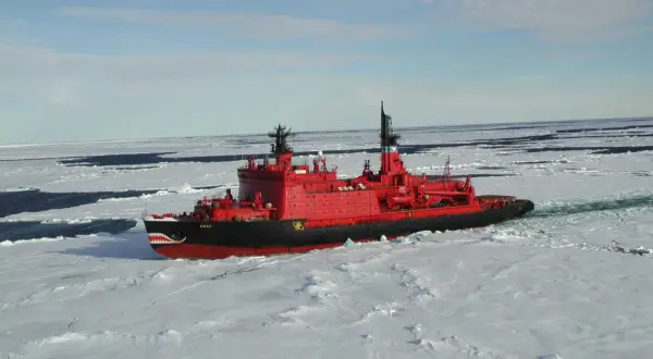Ein rotes Eisbrecher-Schiff mit Haifischzähnen am Bug kämpft sich durch gefrorenes Wasser.