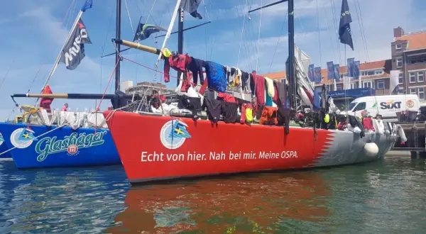 Segelboote im Hafen, Wäsche trocknet an Bord. Michael Illbrucks Boot "Meine OSPA" mit rotem Rumpf und Schriftzug.