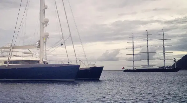 Ein großes, modernes Segelboot liegt neben einem historischen Segelschiff. Ein beeindruckender boat vs ship Vergleich.