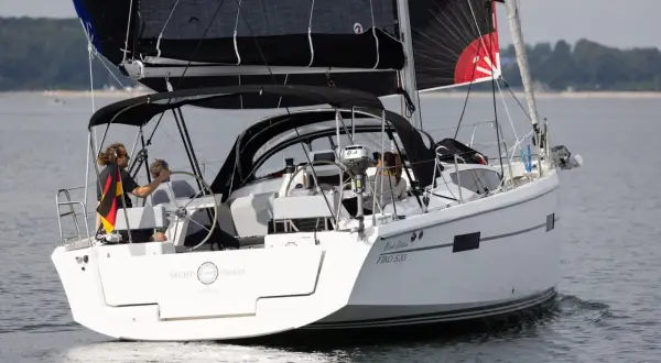 Segelboot mit schwarzem Großsegel und Besatzung, die an das Erbe von Eric Tabarly erinnert.