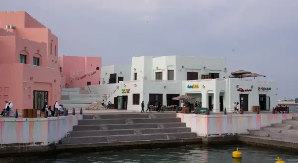 Bunte Gebäude am doha port, mit Menschen, die auf den Stufen sitzen und spazieren gehen.
