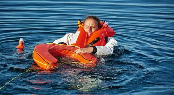 Frau im Wasser mit Schwimmweste und Rettungsring, ein "man overboard" Szenario.