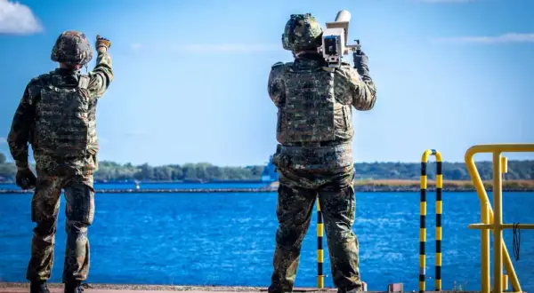 Zwei Soldaten sichern die Küste. Einer richtet eine Waffe, der andere hält ein Gerät. Maritime security in Aktion.