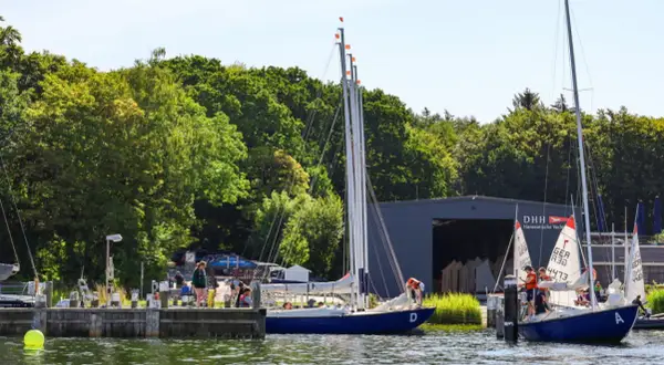 Segelboote am Steg der hanseatischen Yachtschule. Junge Segler üben auf dem Wasser.