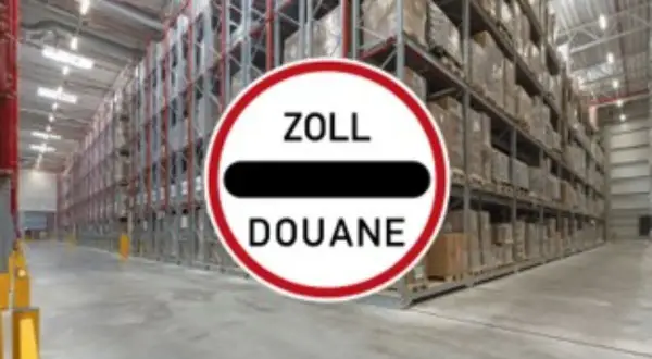 Großes Lager mit hohen Regalen voller Waren. Ein Schild mit "ZOLL DOUANE" weist auf einen bonded store hin.
