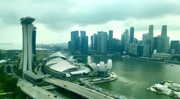 Blick auf die Skyline von Singapur mit dem Marina Bay Sands Hotel, dem ArtScience Museum und dem geschäftigen Singapore Port im Hintergrund.