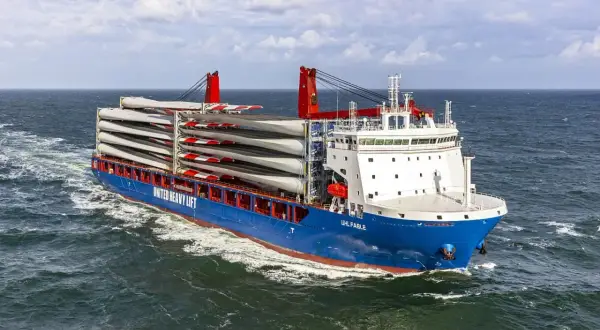 Ein **heavy lift vessel** transportiert viele Rotorblätter für Windkraftanlagen über das Meer.