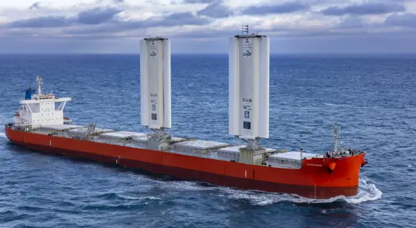 Frachtschiff mit zwei großen Windrotoren für umweltfreundliches tailwind shipping auf dem Meer.