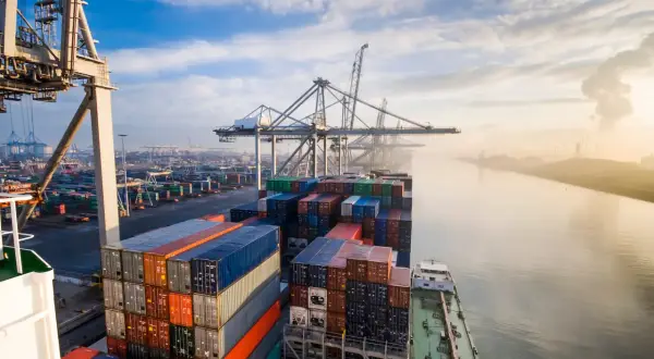 Containerriese in einem geschäftigen Hafen, ein Symbol für europäische Häfen und globalen Handel.