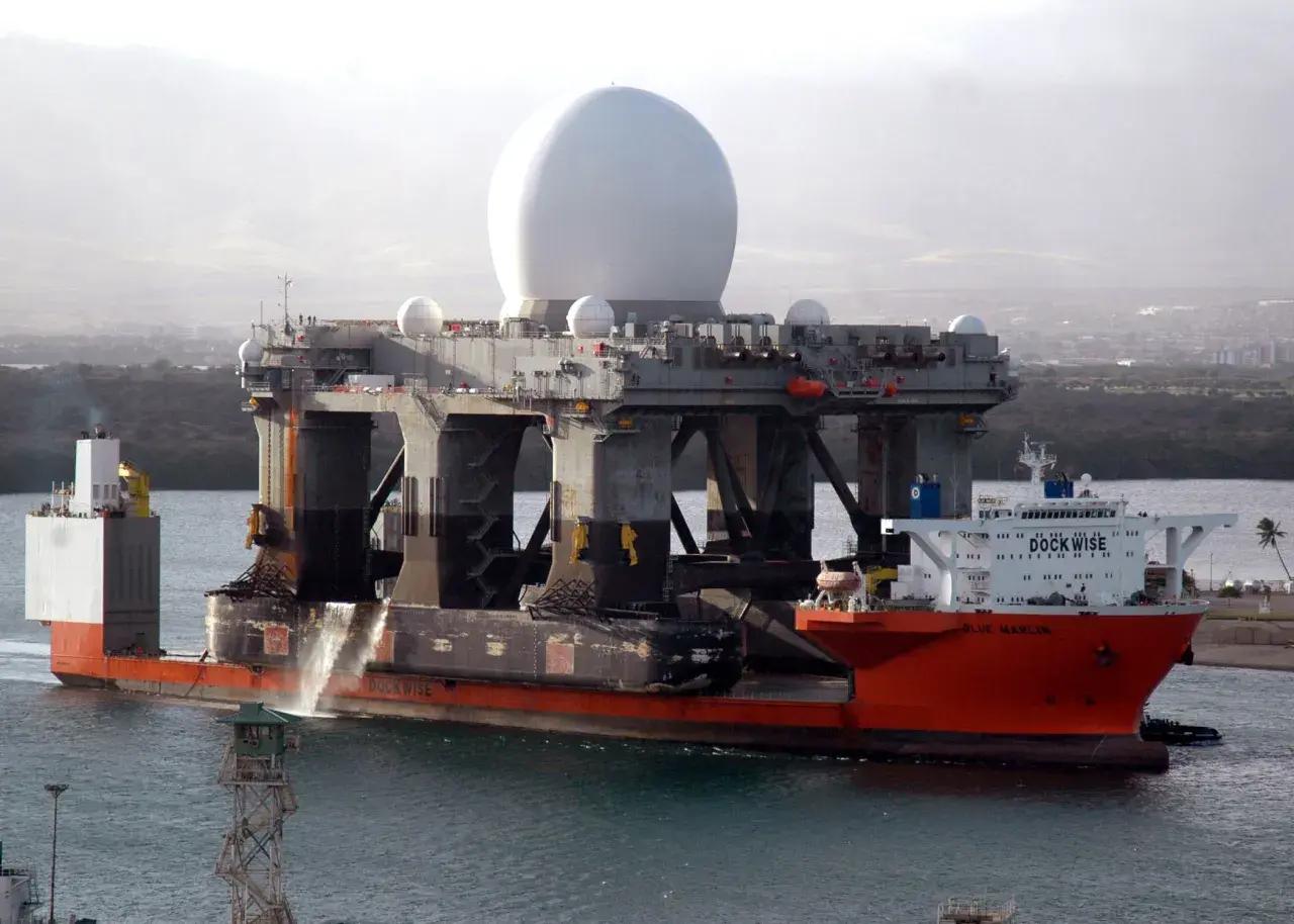 Die orangefarbene "Blue Marlin" ist ein Schwergutfrachter, der eine riesige Plattform mit einer großen weißen Kuppel transportiert.