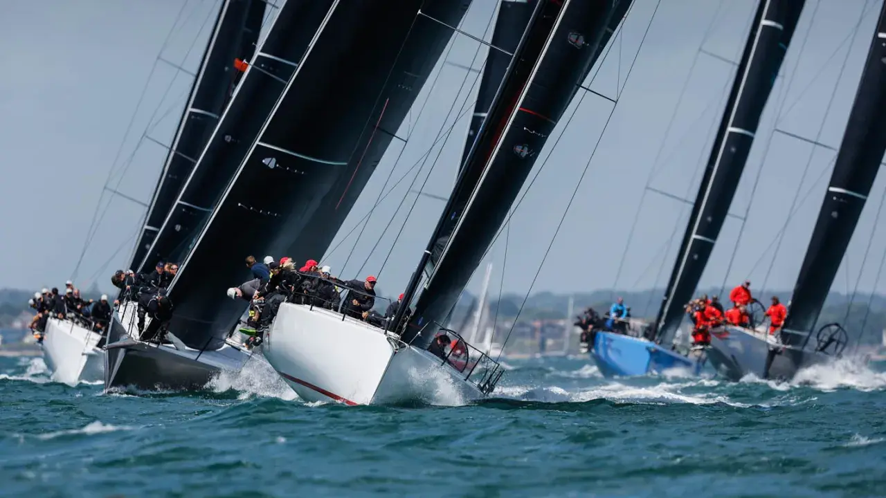 Segelboote kämpfen um die Admirals Cup. Schwarze Segel dominieren, während Teams auf dem Wasser um den Sieg ringen.