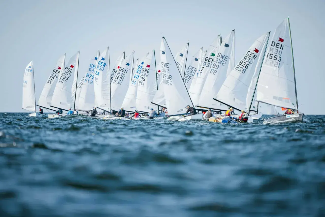 Viele Boote segeln bei der Kieler Woche. Die weißen Segel sind mit Länderkürzeln und Nummern beschriftet.