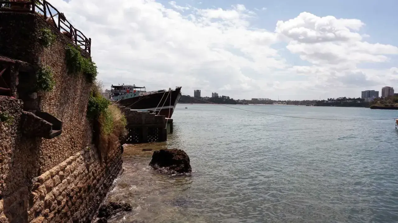 Ein Schiff liegt im Hafen von Mombasa vor Anker. Die Steinküste und Gebäude im Hintergrund zeugen von der geschäftigen Atmosphäre.