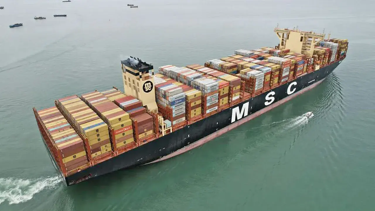 Die MSC Irina, ein riesiges Containerschiff, transportiert Fracht über das Meer. Ein kleines Beiboot fährt nebenher.