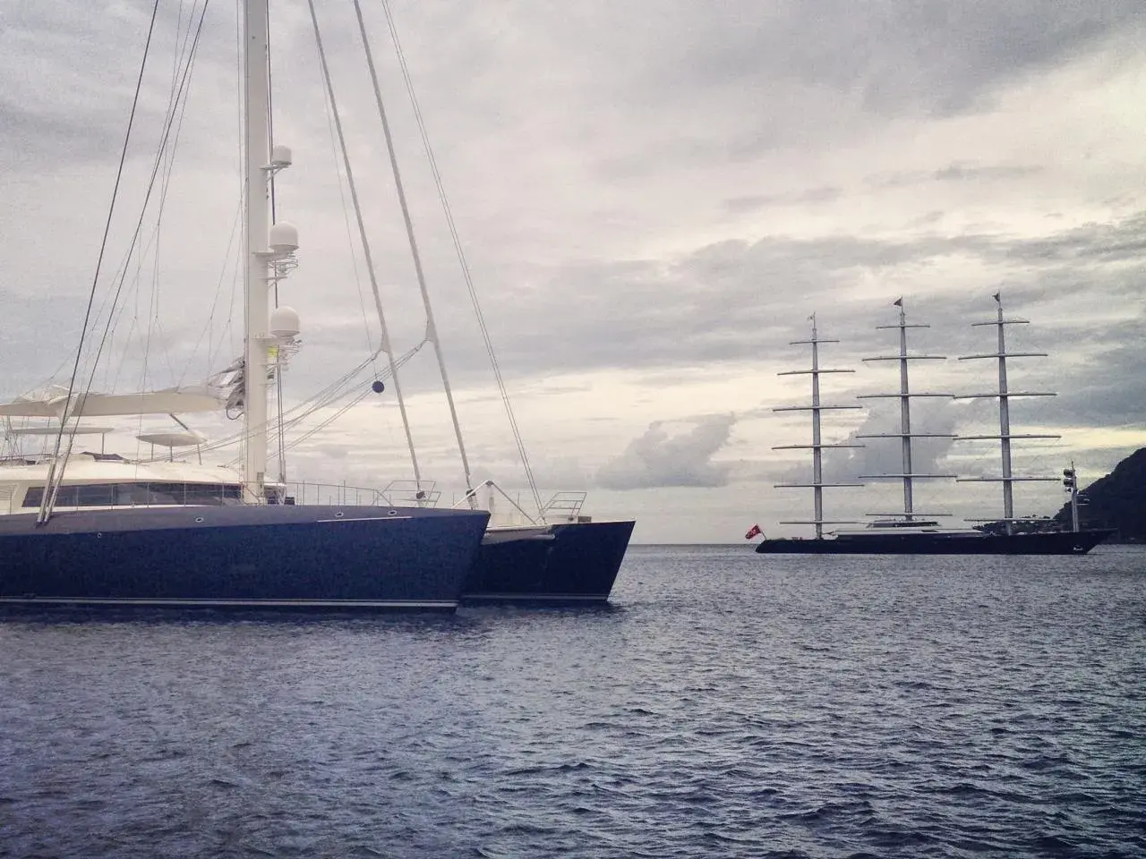 Ein großes, modernes Segelboot liegt neben einem historischen Segelschiff. Ein beeindruckender boat vs ship Vergleich.
