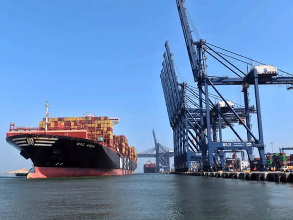 Ein riesiges Containerschiff liegt im Karachi Port vor Anker, während massive Kräne Container verladen.