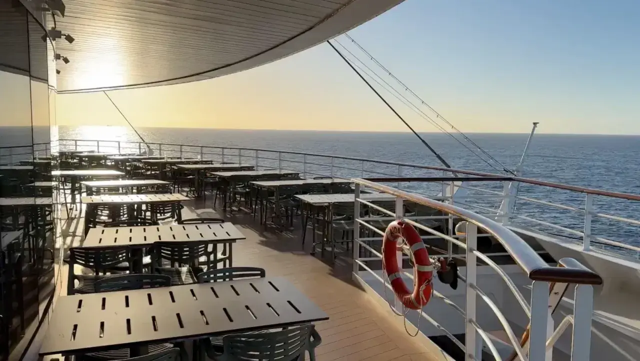 Leere Tische und Stühle auf einem Kreuzfahrtschiff-Deck bei Sonnenuntergang, bereit für die Gäste nach den marine surveys.