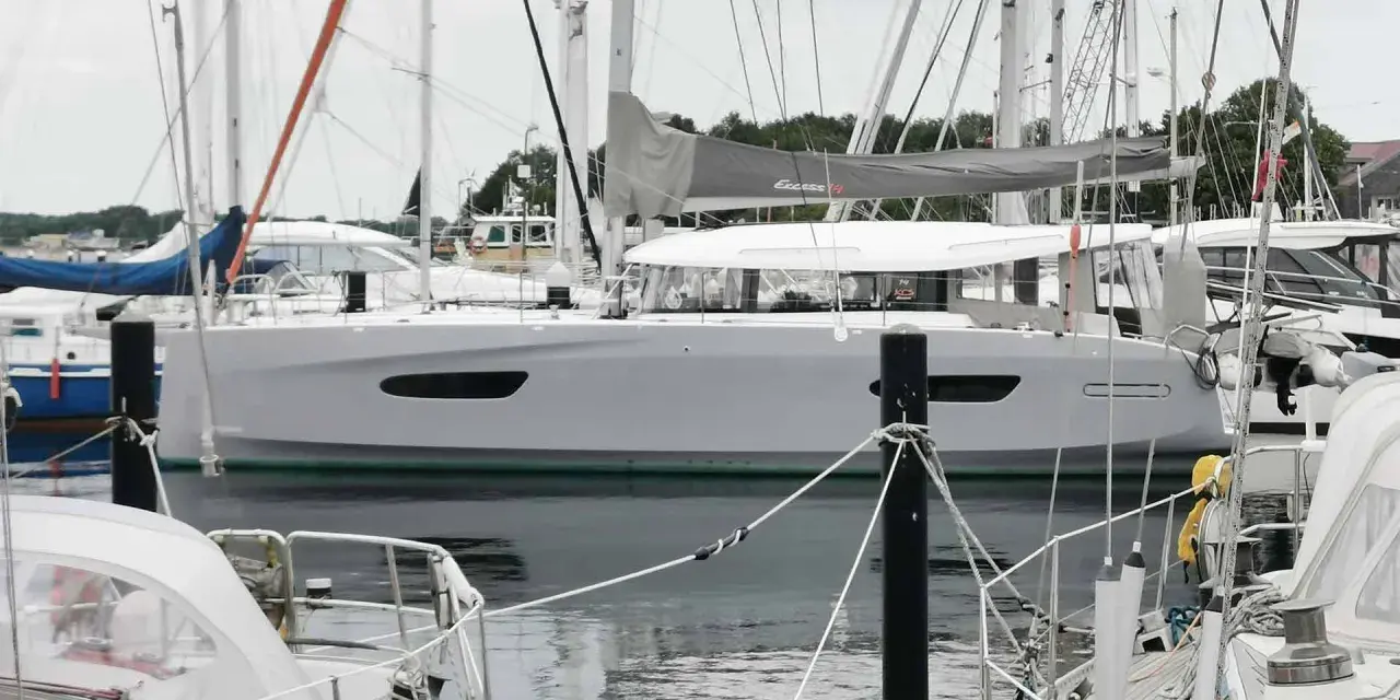 Eine moderne Segelyacht, die Excess 14, liegt im Hafen. Ihr elegantes Design und die großen Fenster versprechen Komfort.