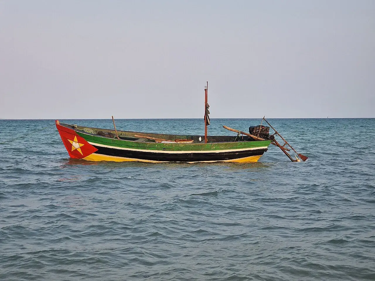 Ein bunt bemalenes Fischerboot treibt auf ruhiger See. Rot, gelb und grün zieren den Rumpf, ein Stern prangt am Bug.
