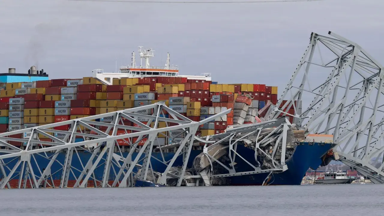 Ein Frachtschiff kollidiert mit einer Brücke, die in sich zusammenfällt. Container sind gestapelt, ein Zeichen für die globale Logistik, die in den US Ports stattfindet.