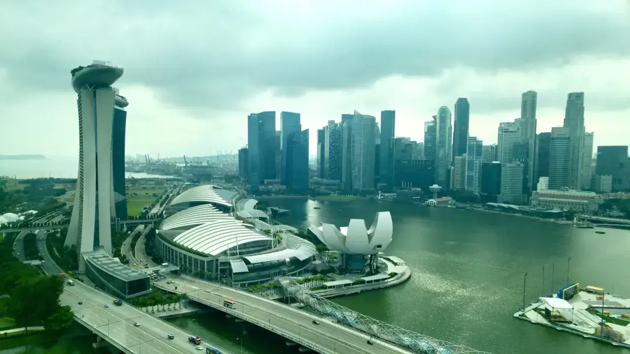 Blick auf die Skyline von Singapur mit dem Marina Bay Sands Hotel, dem ArtScience Museum und dem geschäftigen Singapore Port im Hintergrund.