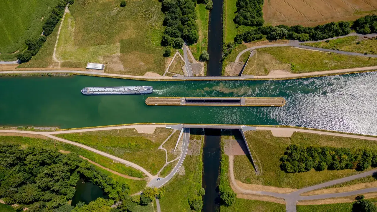 Ein großes Frachtschiff fährt auf einem Kanal. Daneben liegt eine Schleuse, bereit für das nächste Schiff.