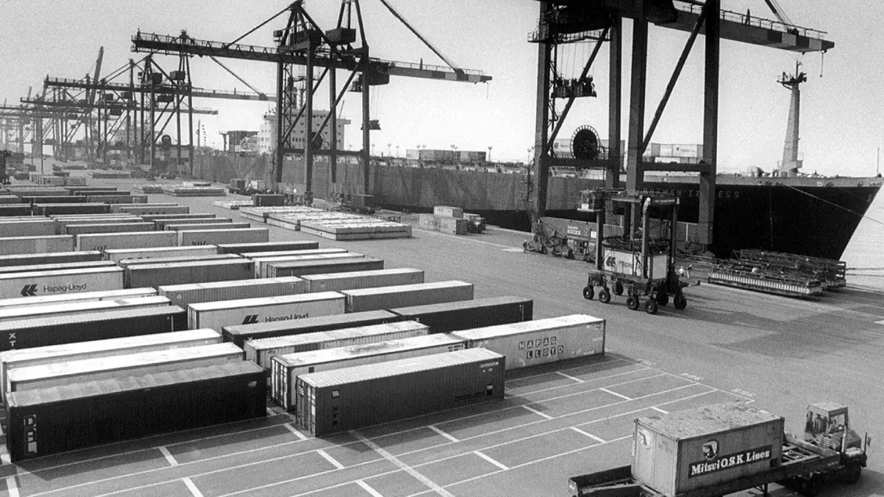 Ein geschäftiger Containerhafen mit vielen vgm container, Kränen und einem Frachtschiff.