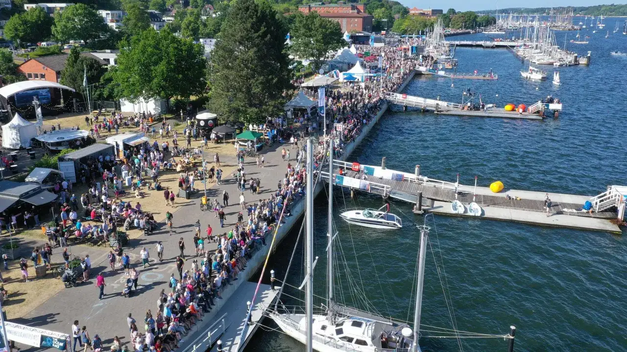 Menschenmassen am Kai, Boote im Wasser, eine Bühne und Zelte – die Kieler Woche, ein Highlight der Kiel Ocean Race Saison.
