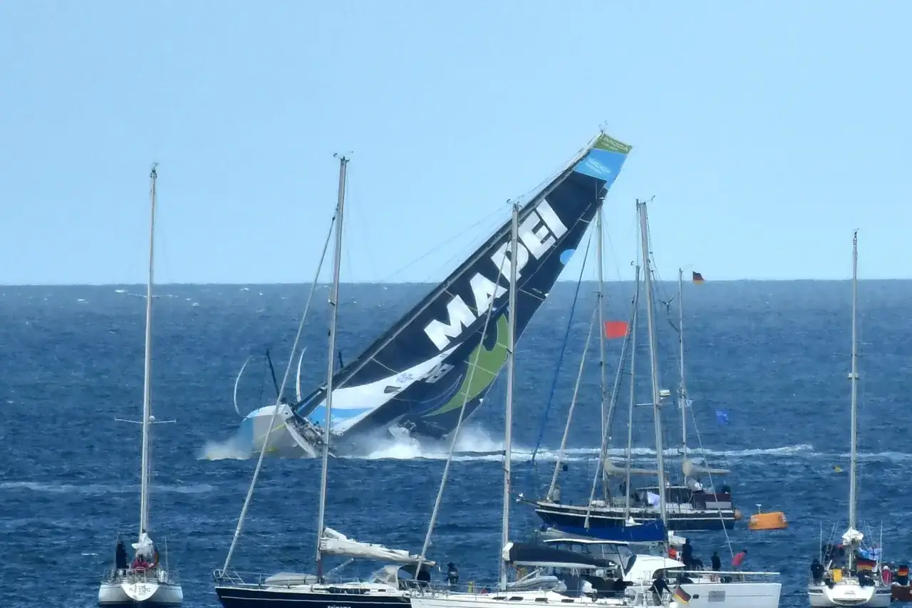 Ein Segelboot kippt dramatisch bei einem Ocean Race Crash. Andere Boote sind in der N&auml;he.