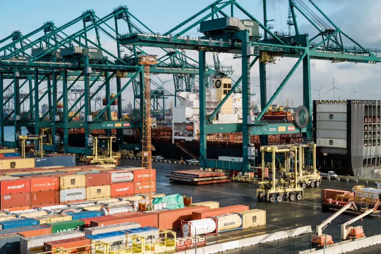 Große Kräne im Hafen beladen ein Schiff mit Containern. Ein bonded store ist hier Teil der globalen Logistik.