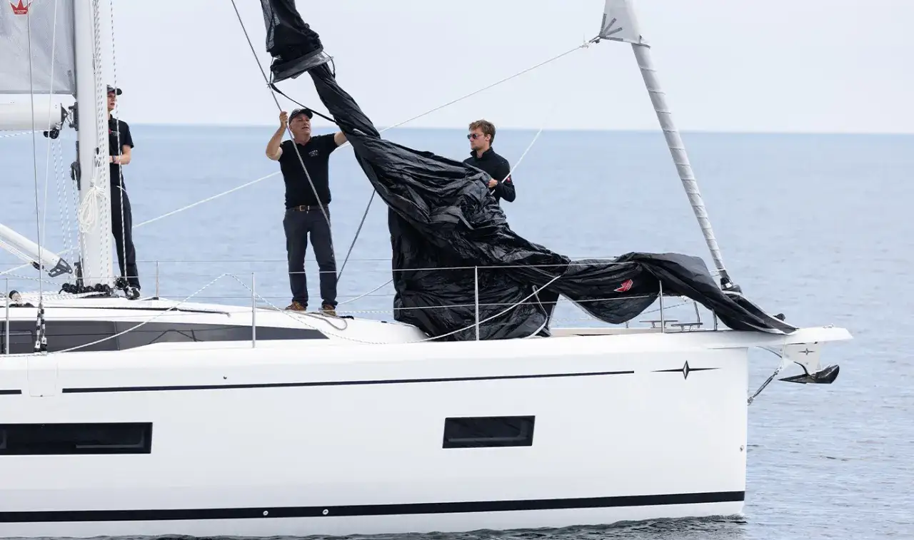 Männer bereiten das schwarze Segel für das Jolle segeln vor.