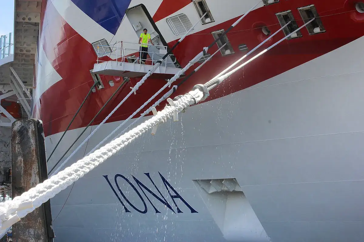 Ein Mann in Warnweste steht auf einem Wartungssteg des moored ship 