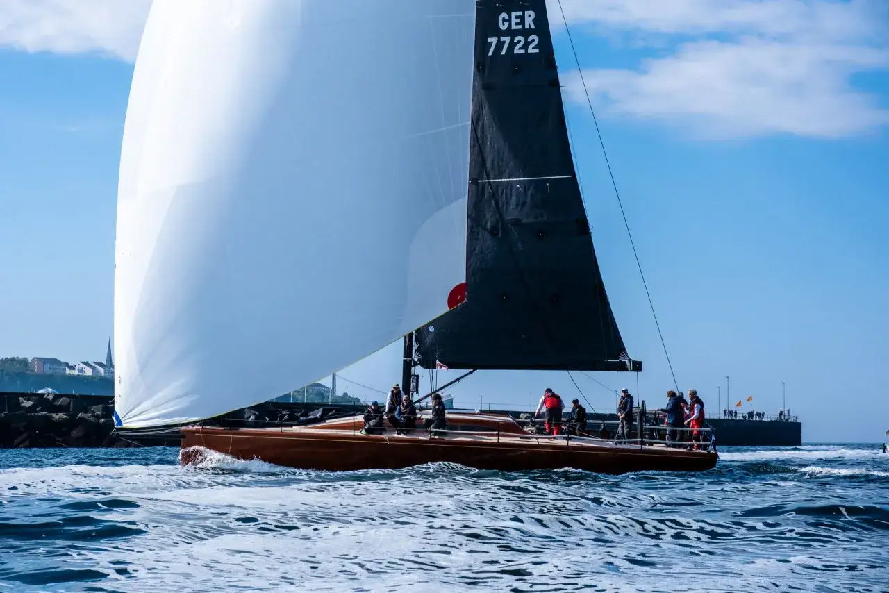 Segelboot mit weißem und schwarzem Großsegel, Nummer GER 7722, auf dem Wasser. Die Crew bereitet sich auf die Admirals Cup Regatta vor.