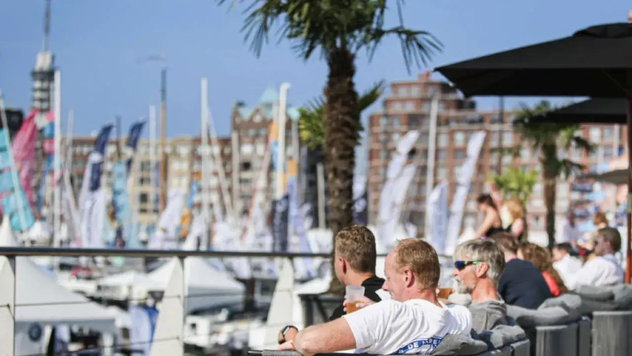 Genie&szlig;en Sie die HISWA te water mit einem Drink in der Hand, w&auml;hrend Boote und Palmen im Hintergrund vorbeiziehen.