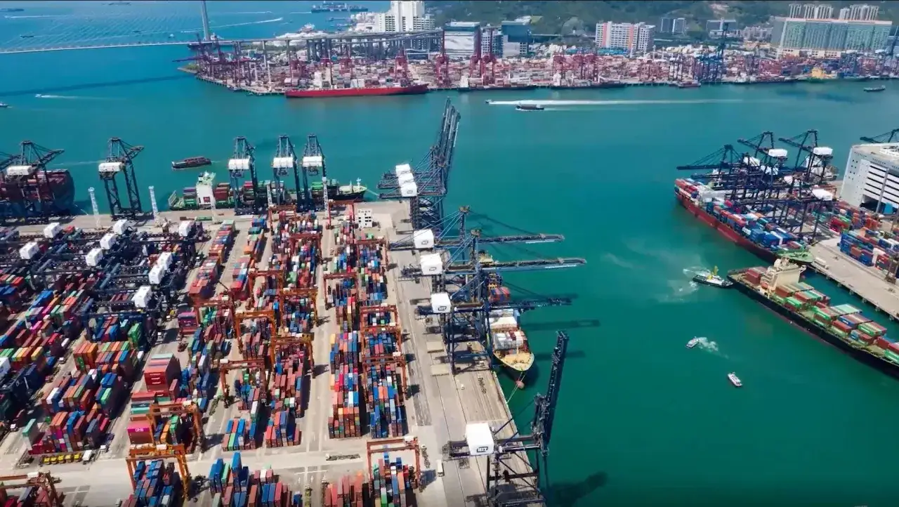 Ein geschäftiger Hong Kong Port mit Kränen, Frachtschiffen und Containern, die auf Verladung warten.