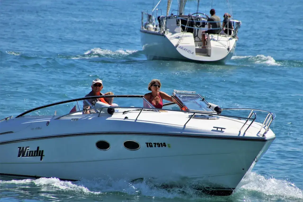 Ein Mann und eine Frau auf einem Motorboot, im Hintergrund eine Segelyacht. Perfekt für marine surveys.