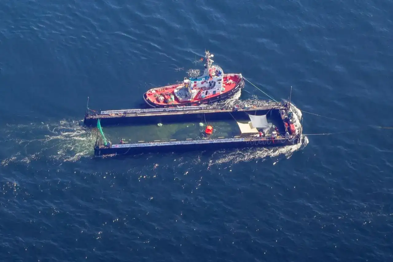 Schlepper zieht Ponton mit grüner Plane und Rettungsring. Smit Salvage-Aktivitäten im Gange.
