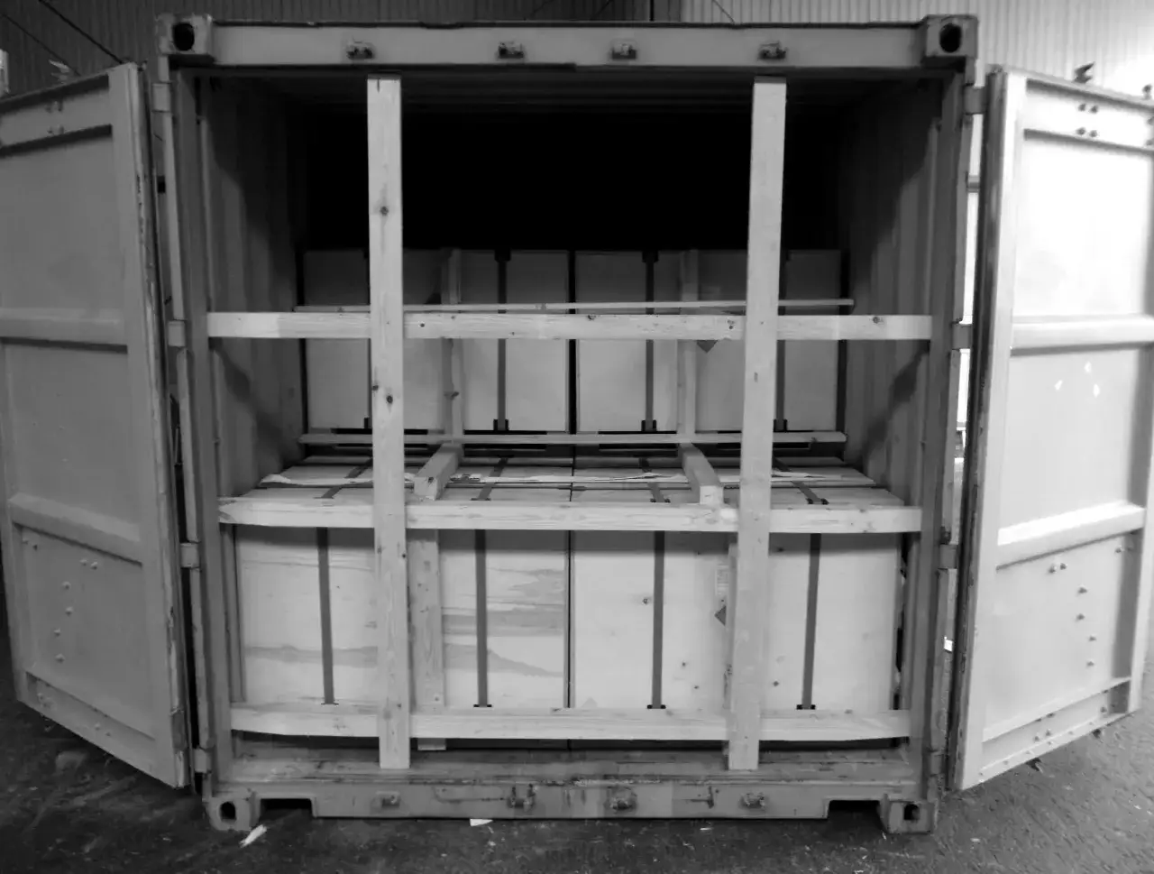 Ein offener Container mit gestapelten Kisten, gesichert durch Holzkonstruktionen. Dies ist ein Beispiel für general cargo, bereit für den Transport.