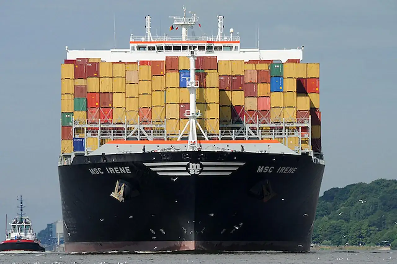 Die MSC Irene, ein riesiges Containerschiff, fährt auf dem Wasser. Ein Schlepper begleitet sie.