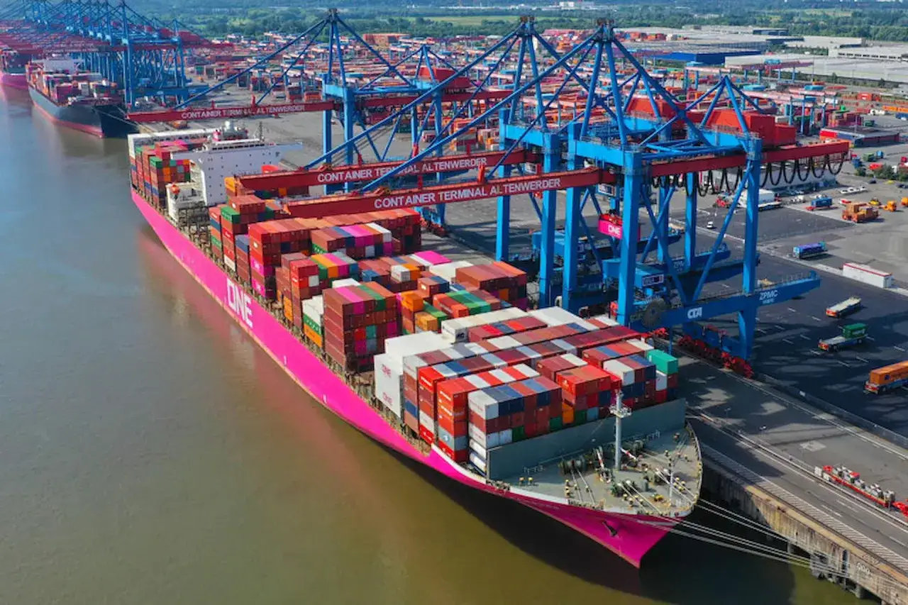 Großes Containerschiff mit vielen bunten Frachtcontainern liegt im Hafen. Kräne laden einen weiteren conex container.