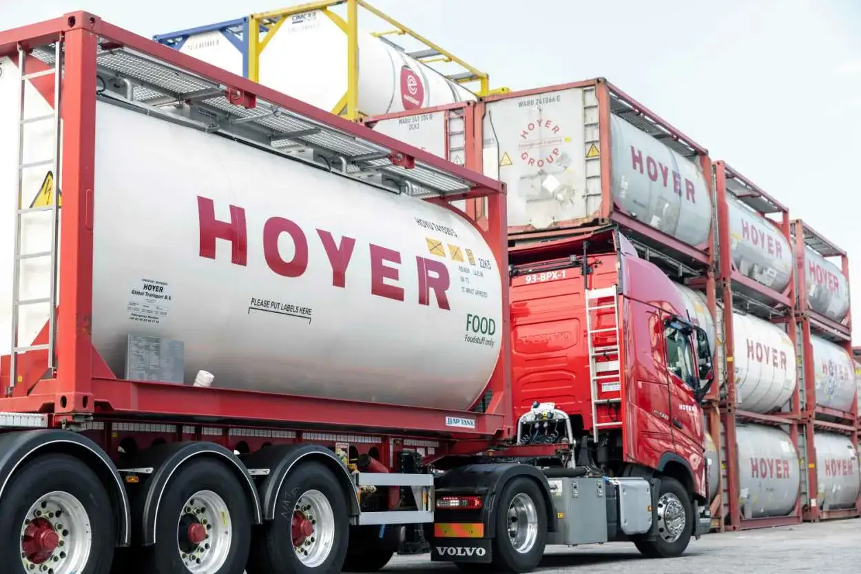 Ein roter LKW mit einem großen weißen Tankauflieger mit der Aufschrift