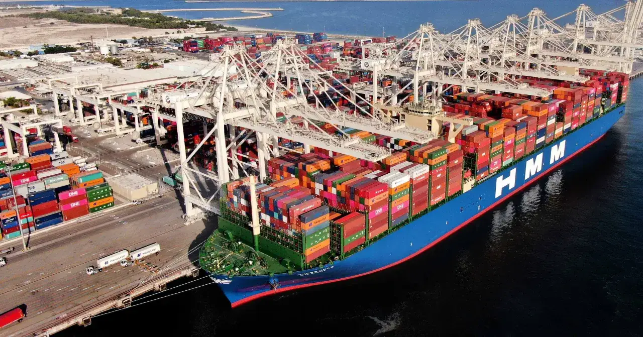 Gigantischer Frachter im Jebel Ali Port, beladen mit bunten Containern, bereit für die Weiterreise.